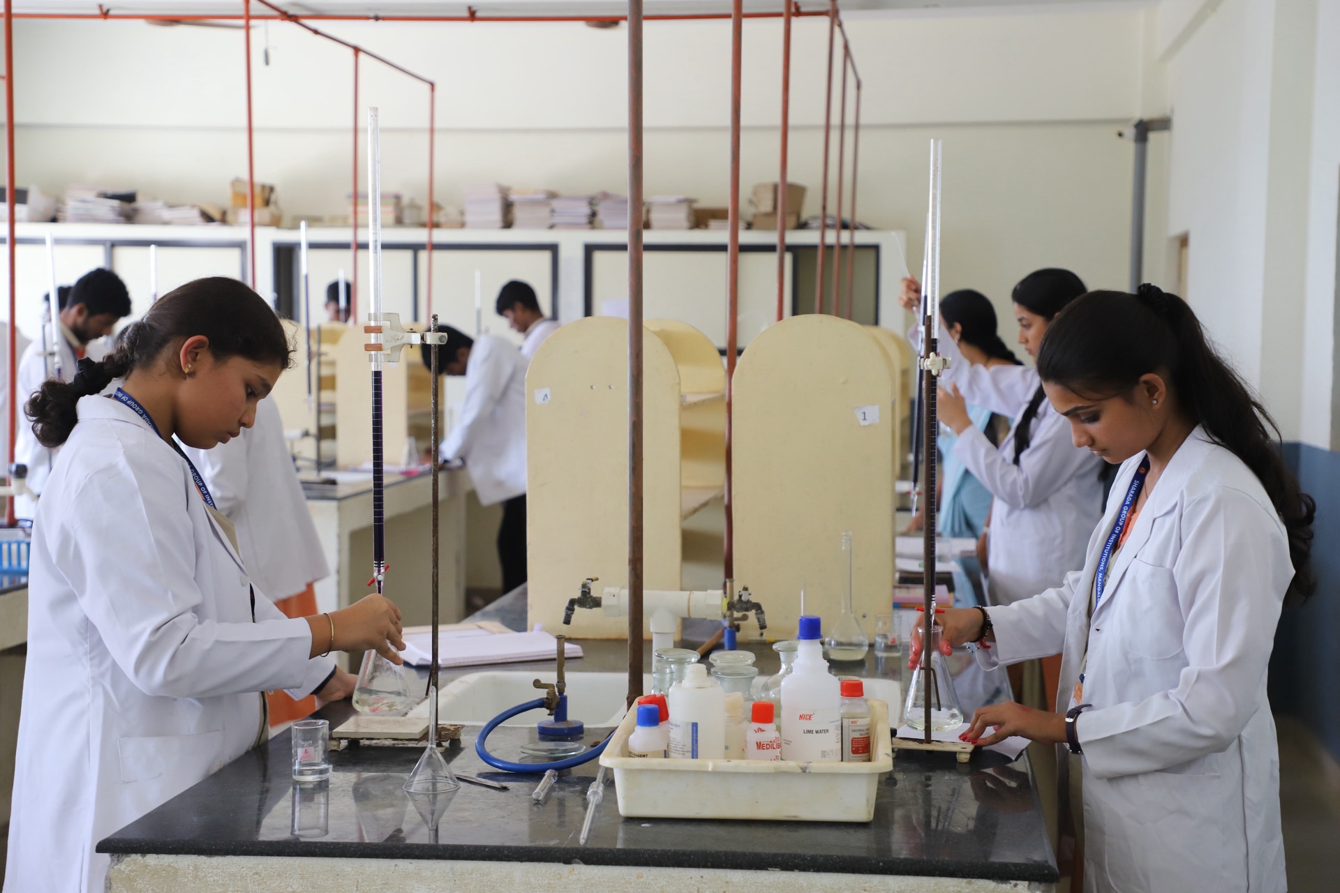 Students in lab coats performing a titration in the chemistry laboratory