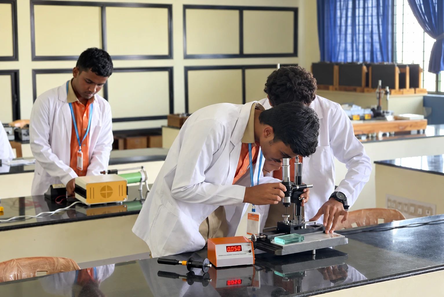 Science students measuring with a travelling microscope in the physics laboratory
