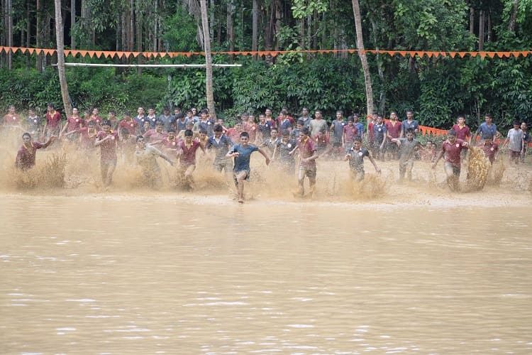 Students racing through a muddy paddy field